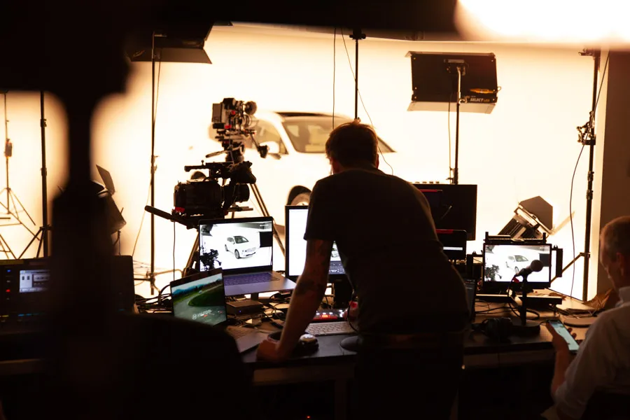 Techniker an der Streaming-Regie, im Hintergrund das Studio mit Auto