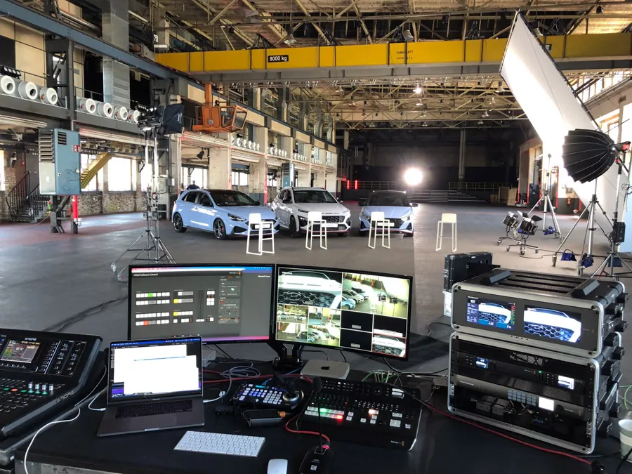 Streaming-Regie in einer Industriehalle mit Autos und Licht